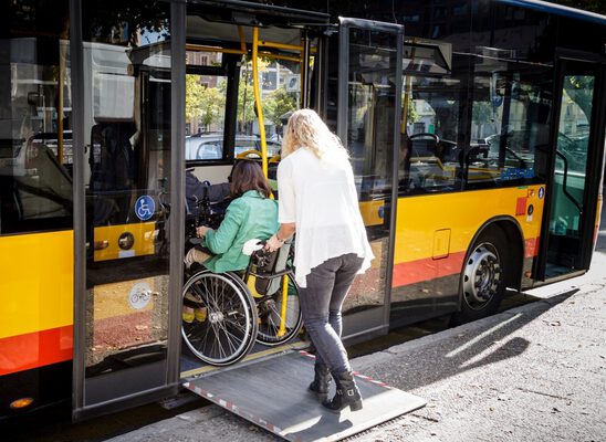 EIne Frau schiebt eine Rollstuhlfahrerin in den Bus